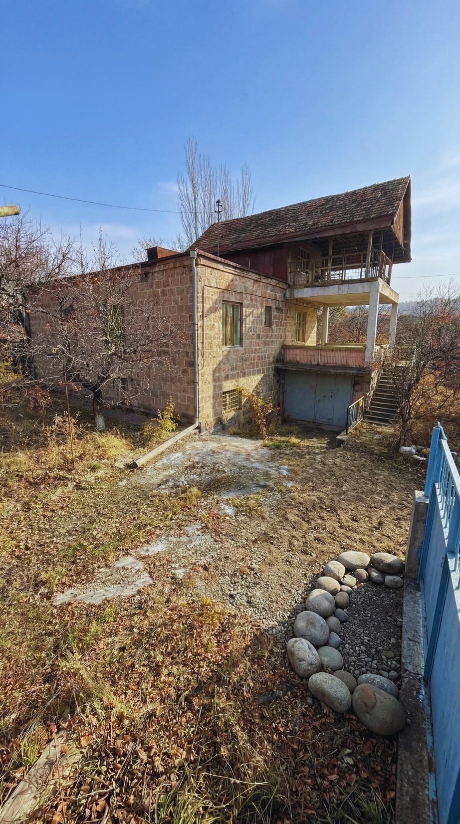 Exterior of the three-level stone house with external stairs, current condition