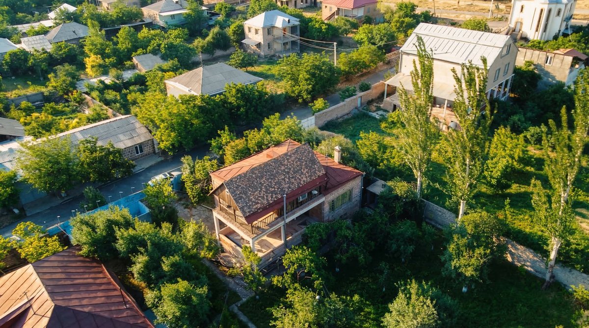 House with red roof among the trees of the plot, exterior view