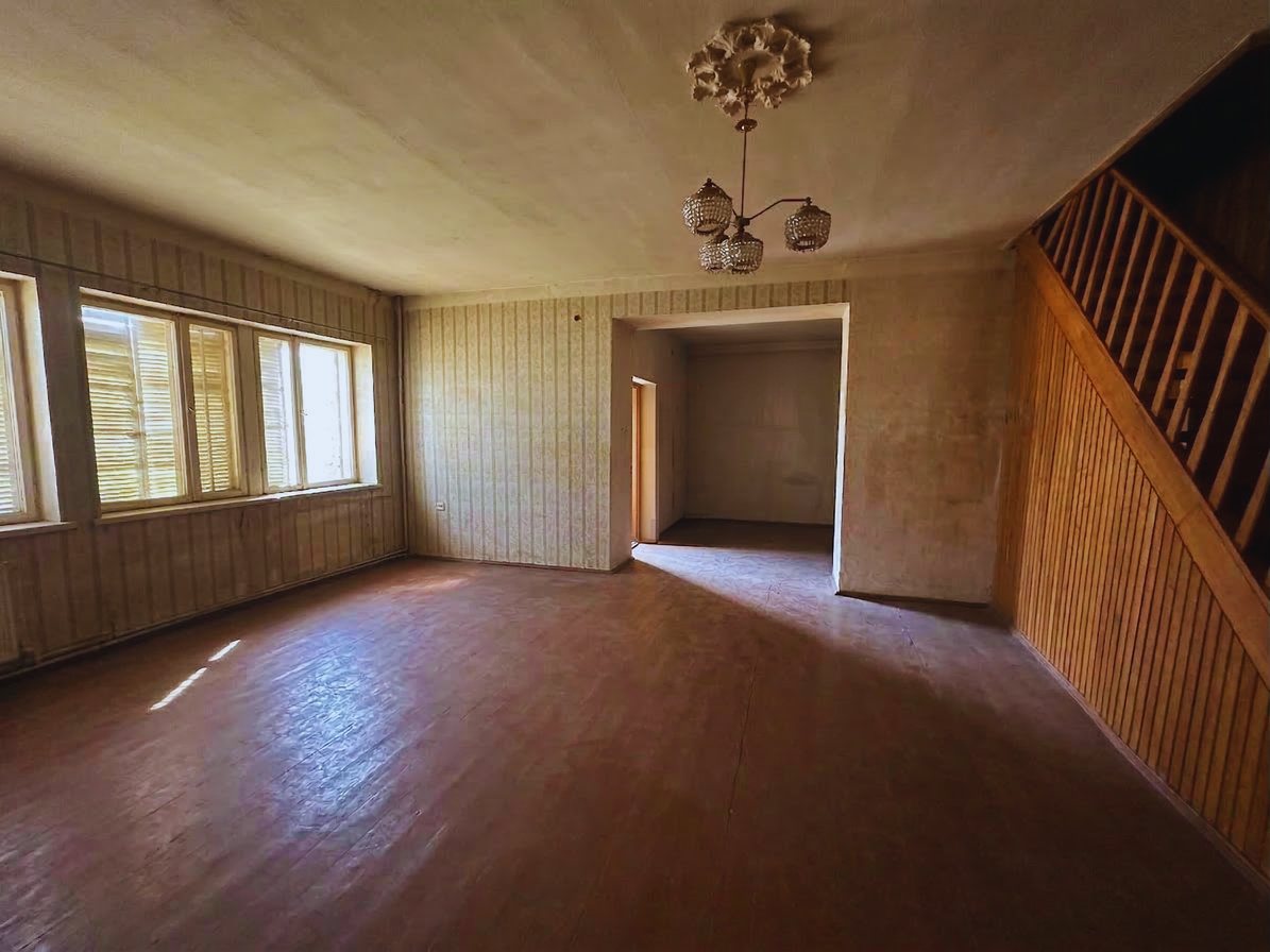 Wood-panelled living space with staircase, current condition
